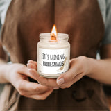 a woman holding a candle that says it's raining bridesmaids