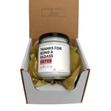 a white candle in a box with a brown ribbon around it