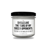 a white jar with a black lid that says smells like the tears of my soccer